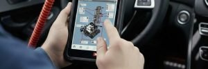 Close-up of a hand using a digital scanner for ABS light diagnostics on a car dashboard during a mobile call-out in Manchester.